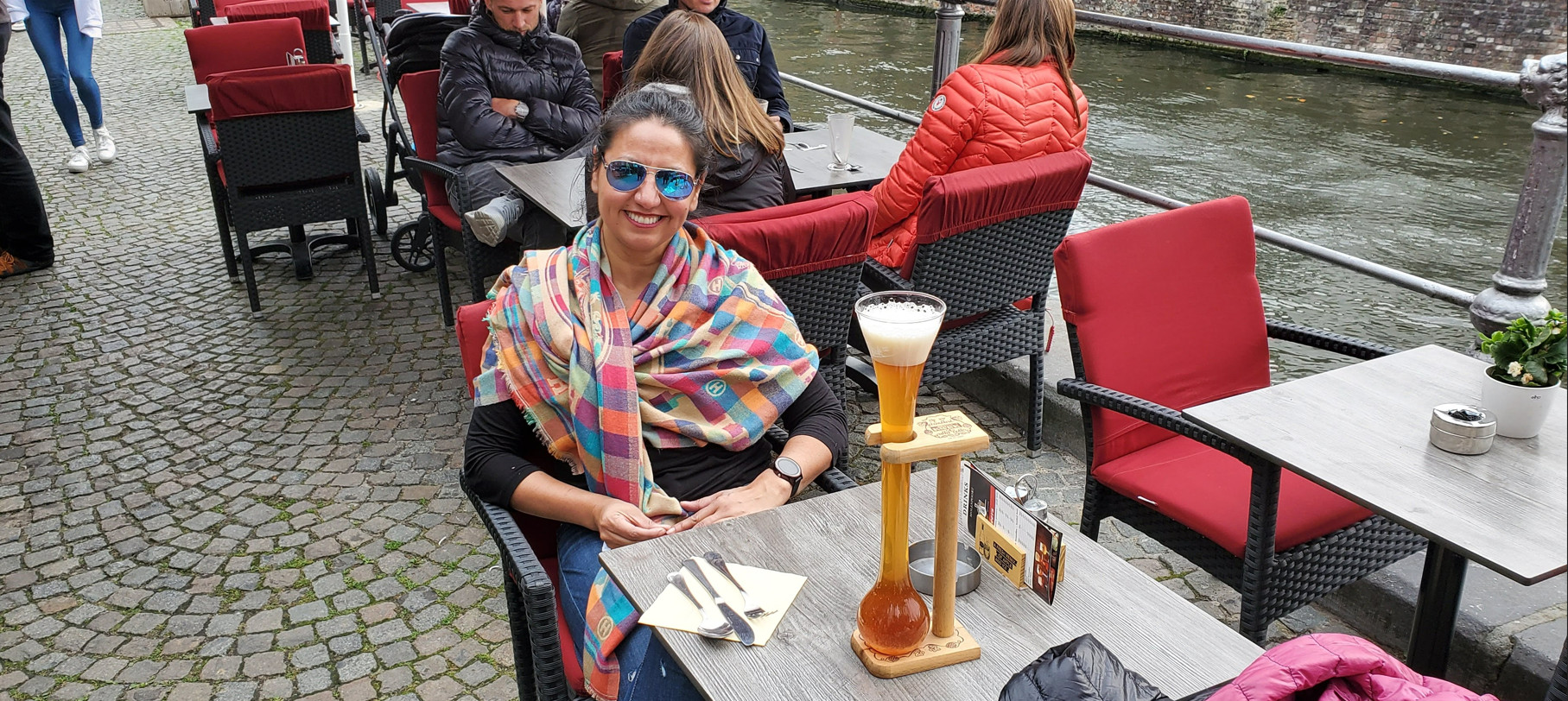 a woman sitting by the river with a kwak glass